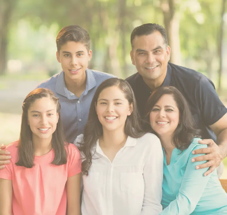 Family of five, consisting of a man and three women, sitting on a bench in a park