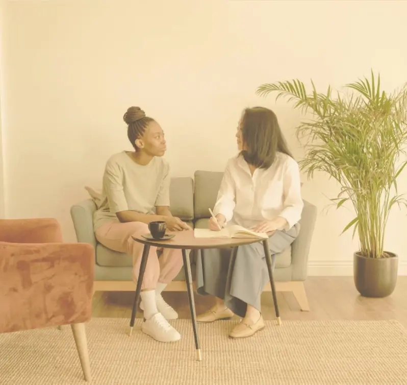 Two women sitting on a couch, engaged in conversation